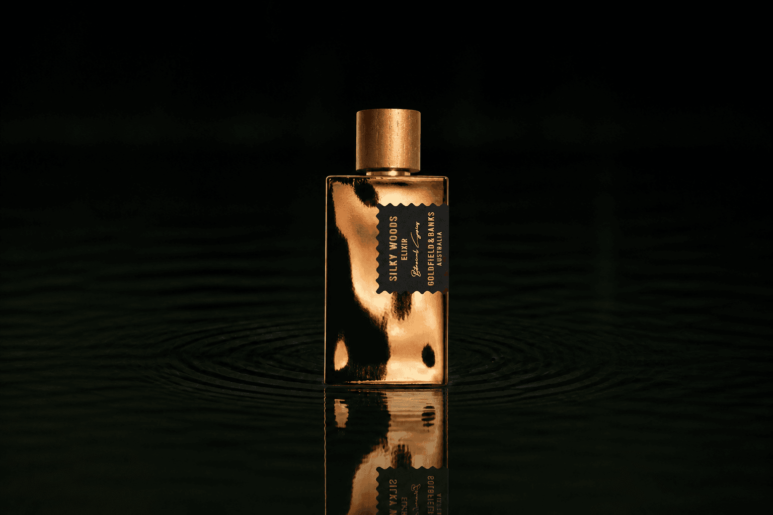 Goldfield & Banks Silky Woods Elixir fragrance bottle floating above dark water