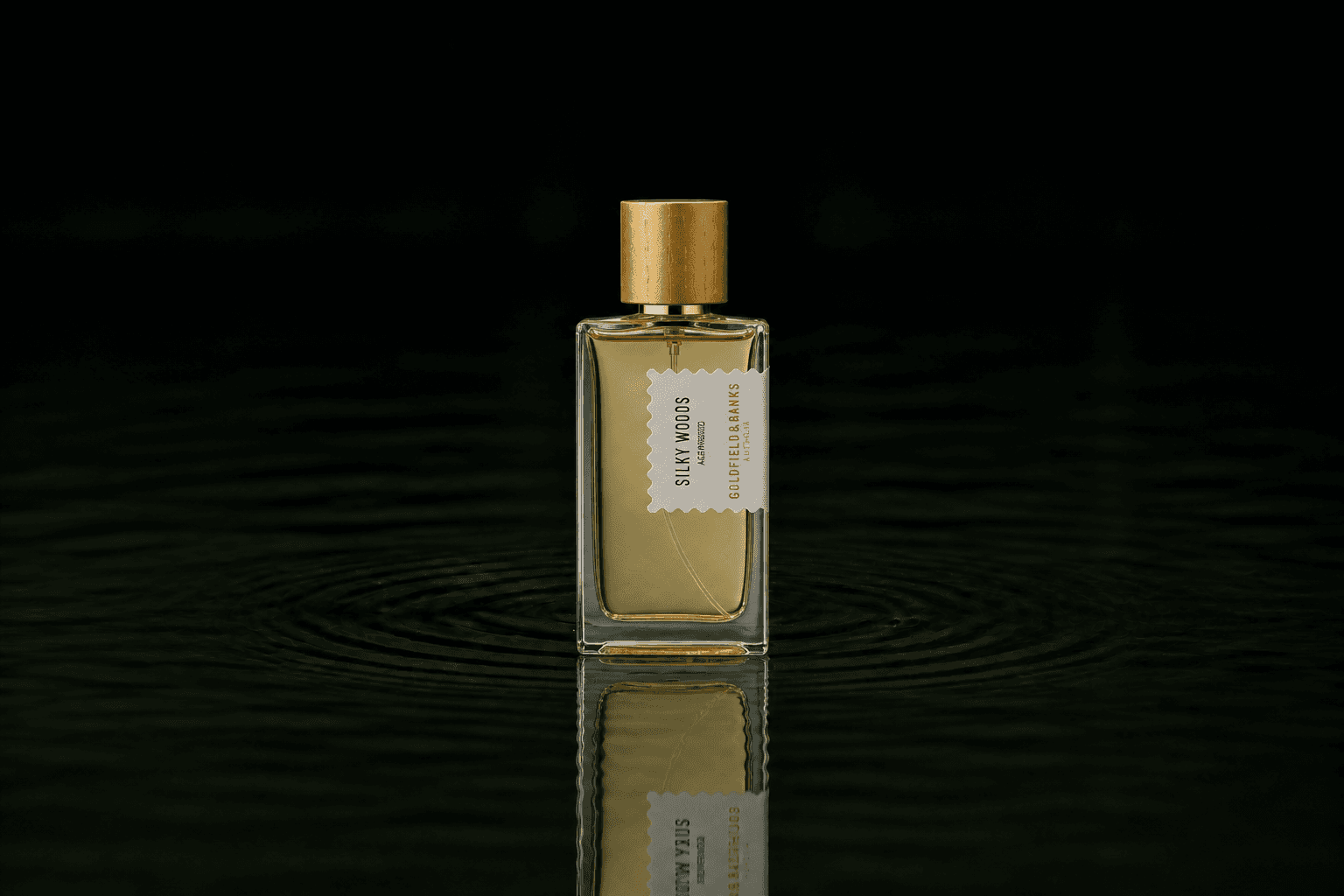 Goldfield & Banks Silky Woods fragrance bottle floating above dark water