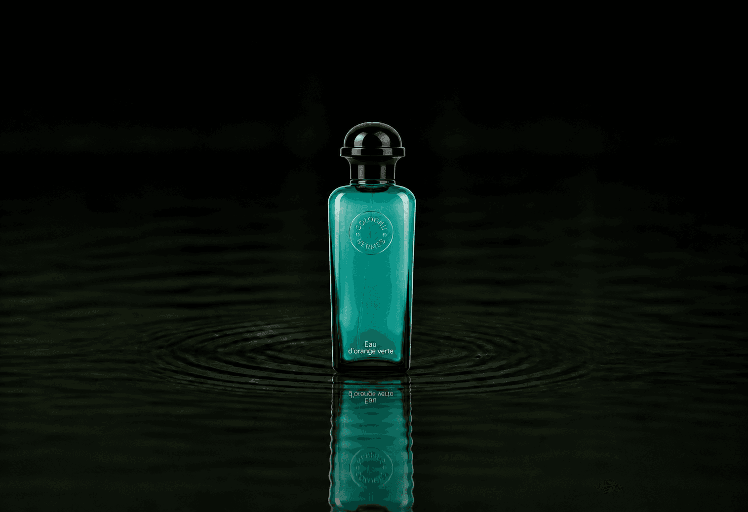Hermes Eau D'Orange fragrance bottle floating above dark water