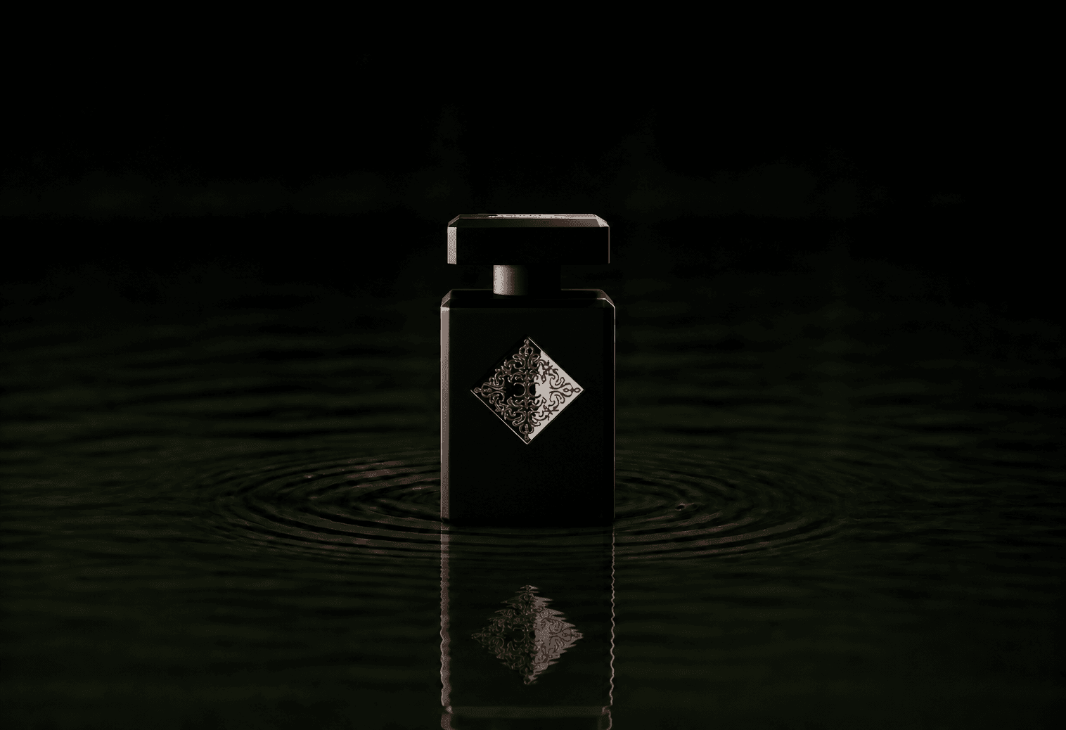 Initio Blessed Baraka fragrance bottle floating above dark water
