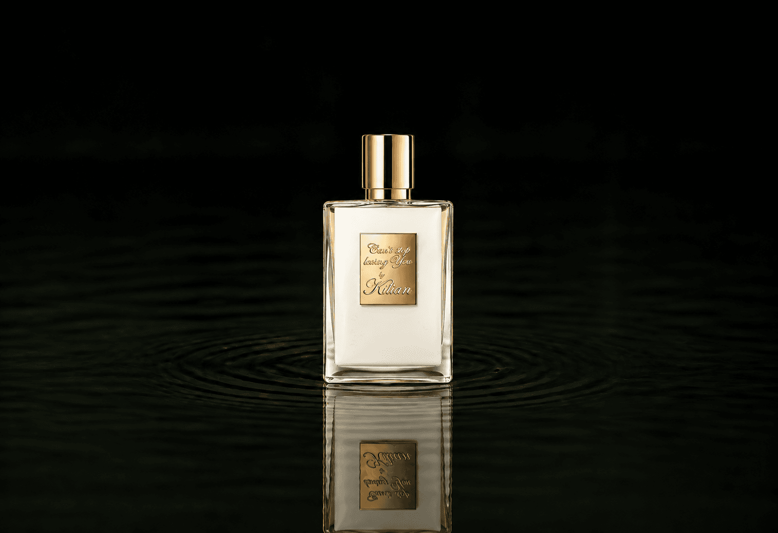 Kilian Can't Stop Loving You fragrance bottle floating above dark water