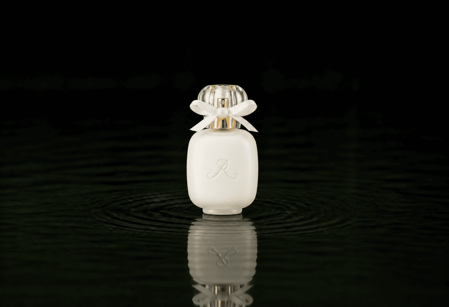 Les Parfums De Rosine Le Magnolia De Rosine fragrance bottle floating above dark water