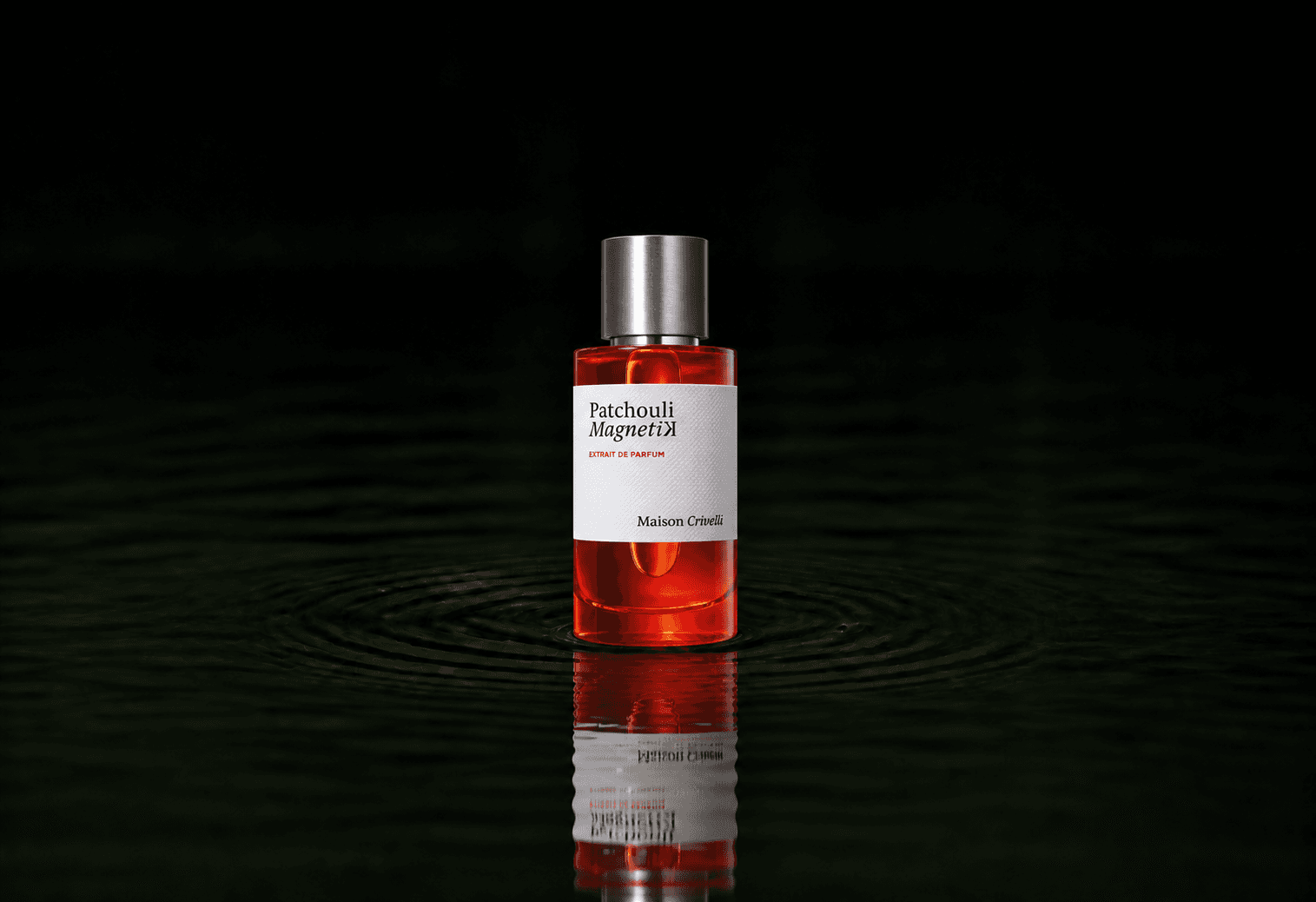 Maison Crivelli Patchouli Magnetik fragrance bottle floating above dark water