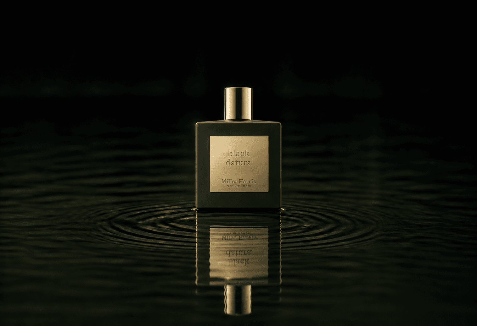 Miller Harris Black Datura fragrance bottle floating above dark water