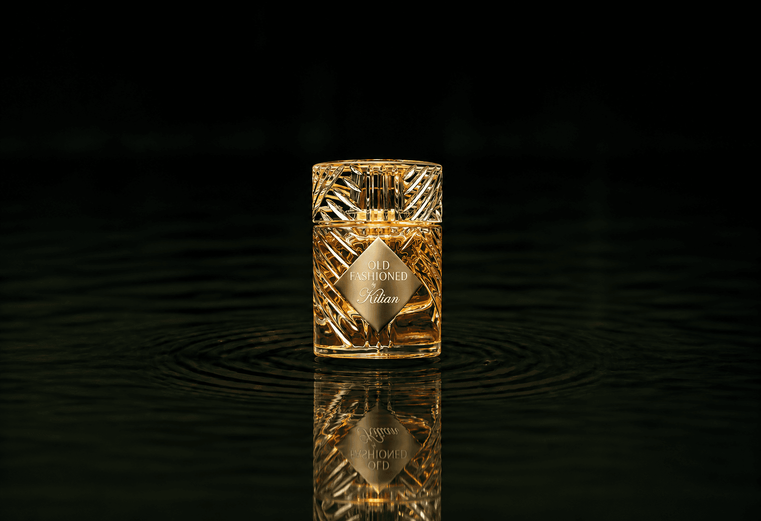 Kilian Old Fashioned fragrance bottle floating above dark water